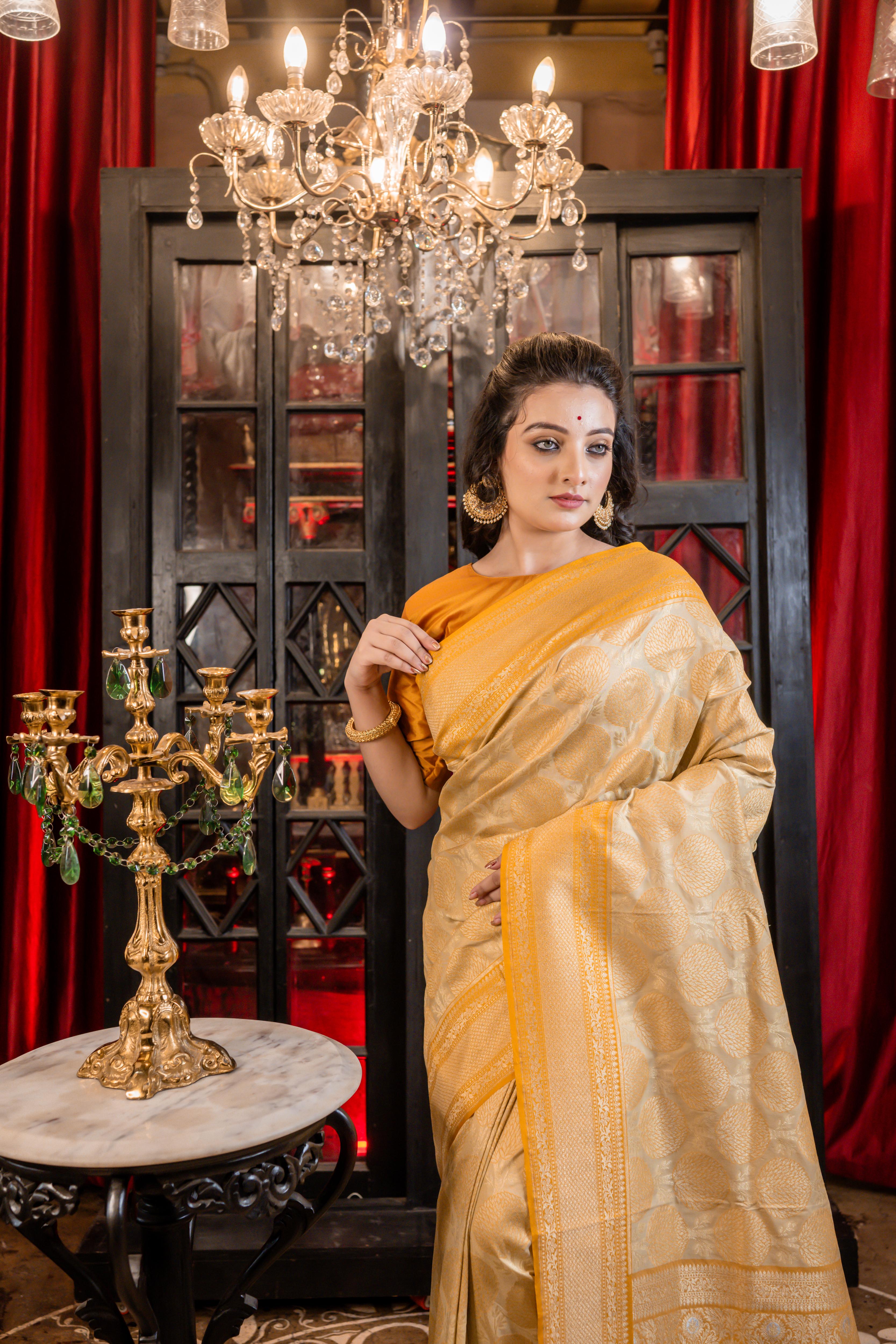 Varnika || Beige Base Matka Silk Banarasi Saree with Mango Yellow border and all over Tree motif woven in Matte Gold Zari