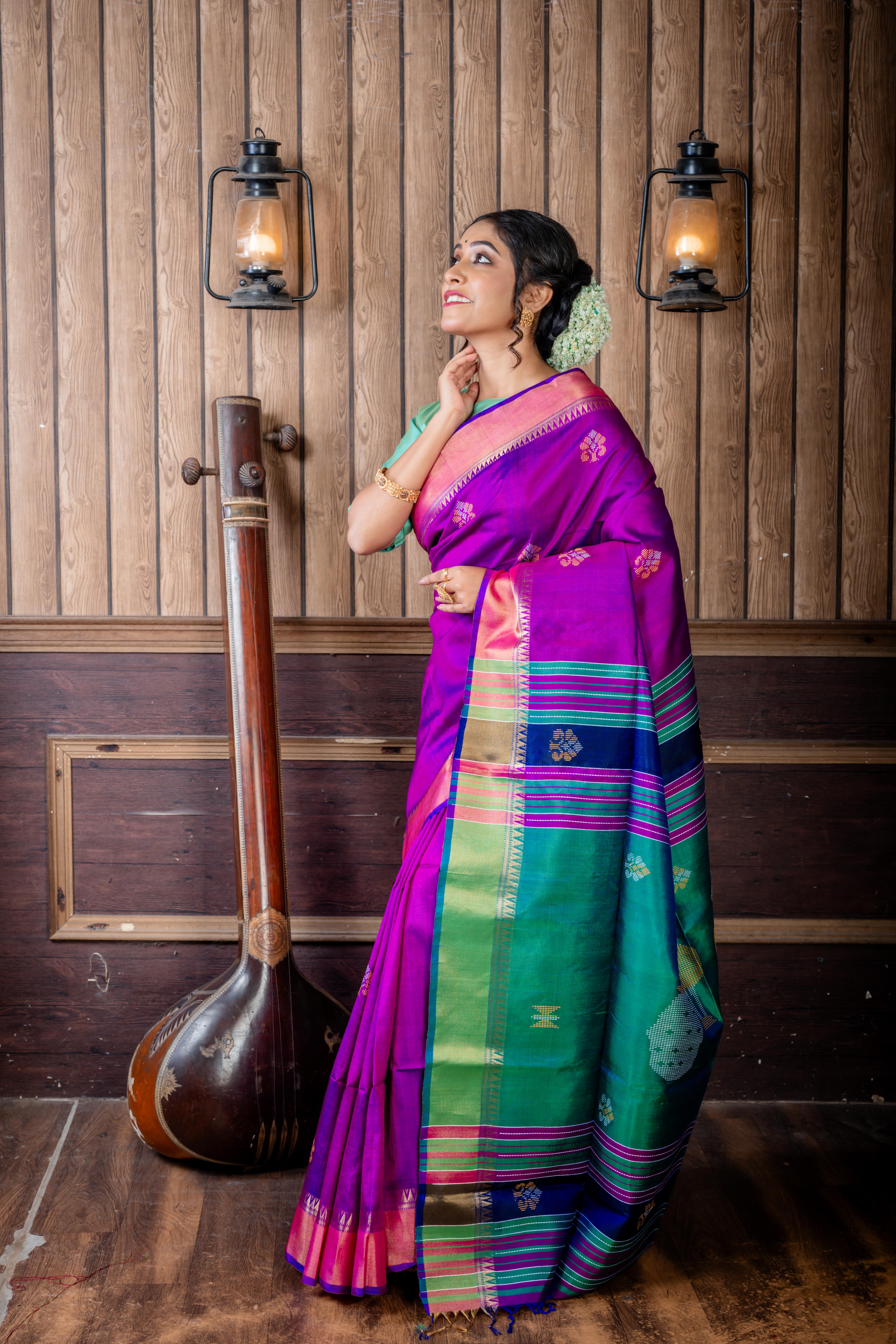 Pritha || Purple & Royal Blue dual tone Pure Bishnupuri Katan Handloom 'Kalakshetra' Embroidery Saree with all over Multi-colour Floral Buta and Stripe & 'Peacock' motif Green Pallu