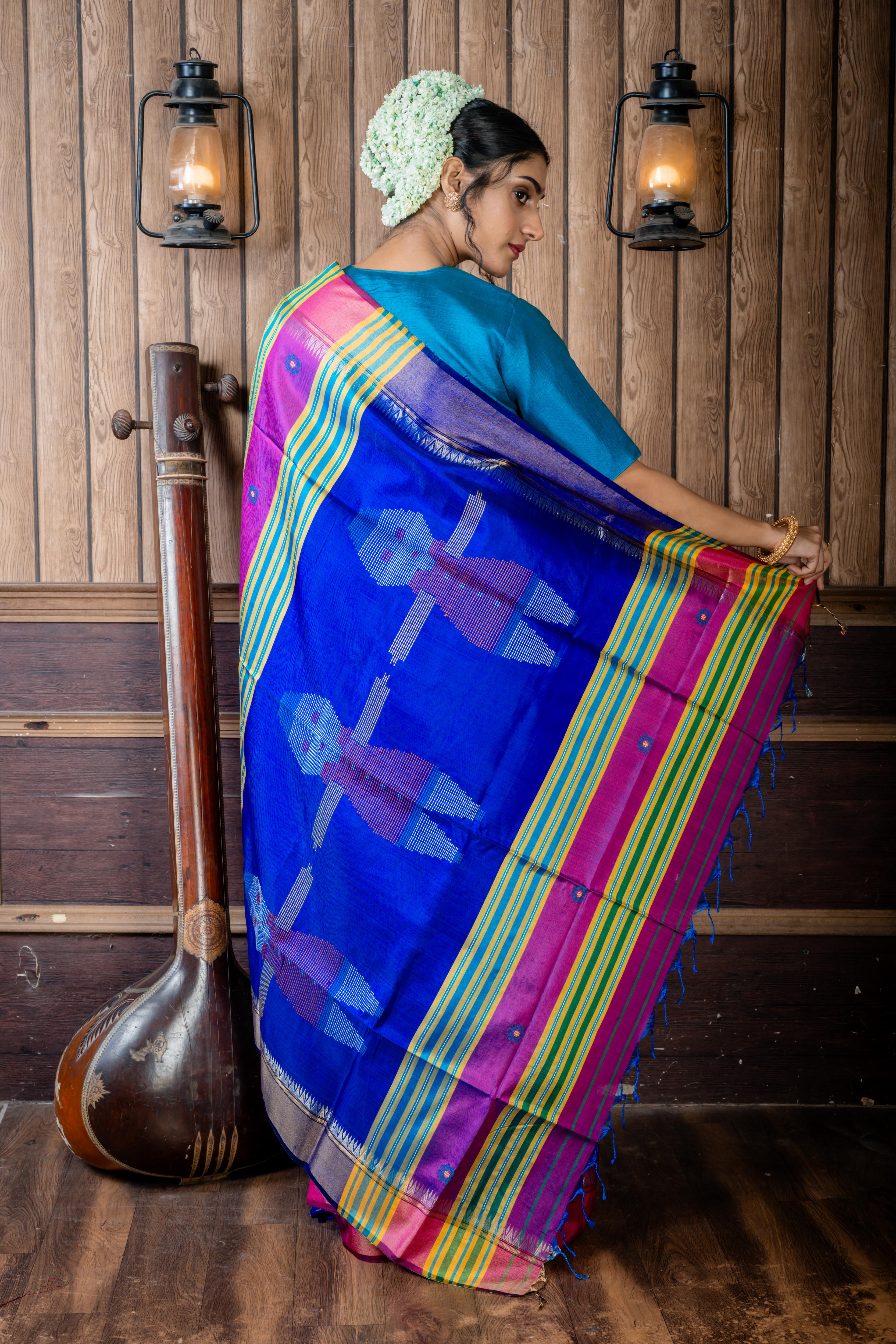 Dotara || Purple & Peacock Blue dual tone Pure Bishnupuri Katan Handloom 'Kalakshetra' Embroidery Saree with all over Multi-colour Floral Buta and Stripe & 'Tribal Doll' motif Pallu